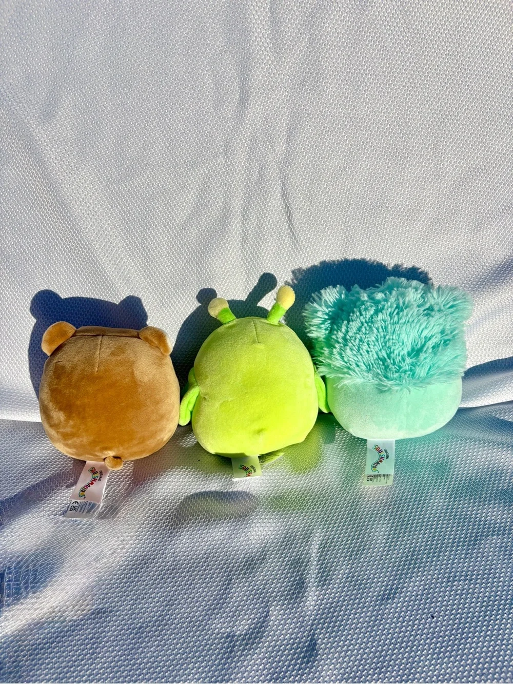 Squishmallows brown Bear, teal Bigfoot, and green grasshopper